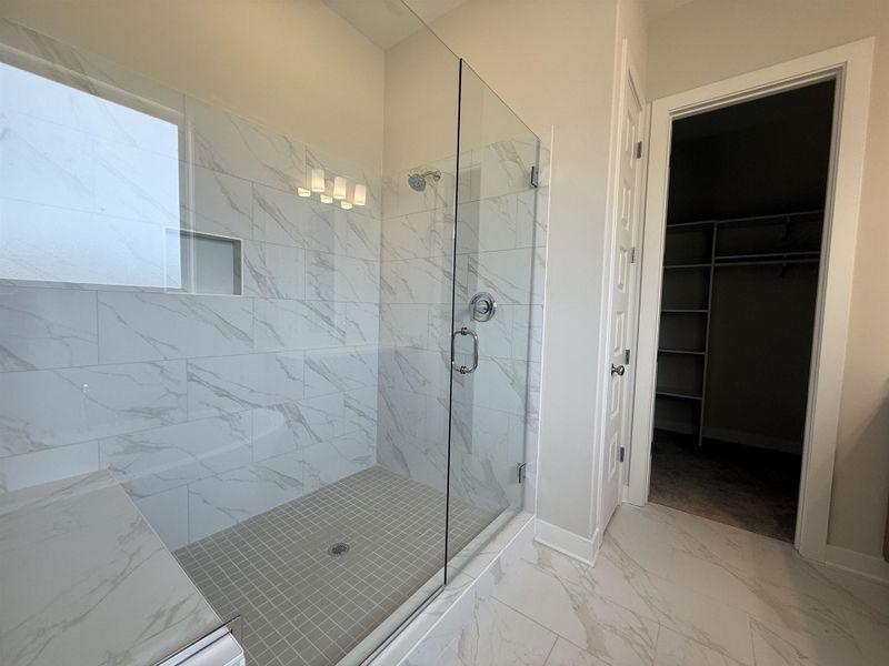 Bathroom with light marble finish floors, a marble finish shower, and a walk in closet