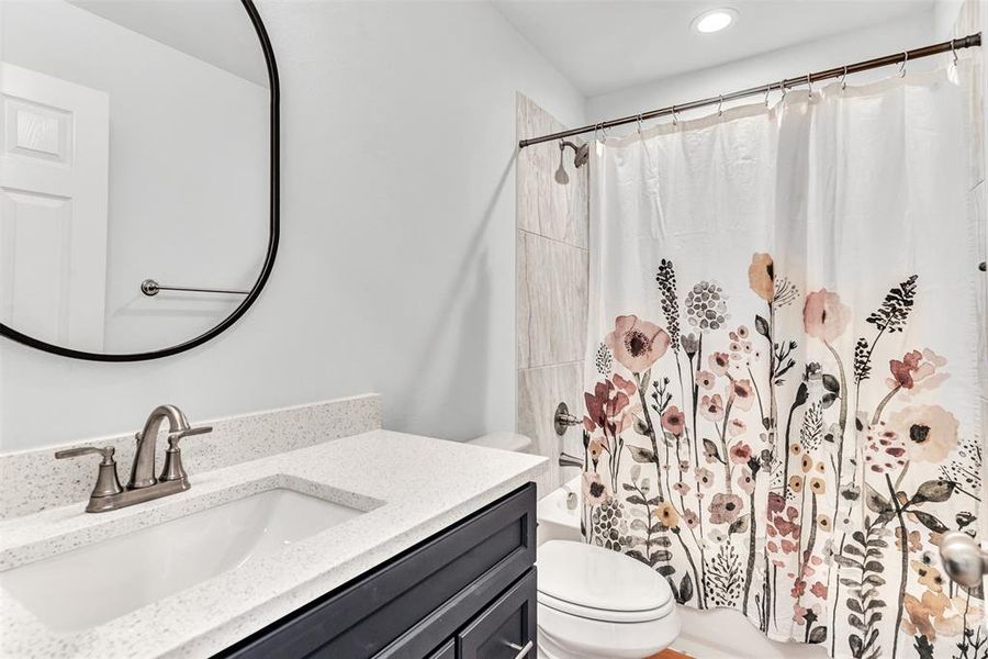 Full bathroom featuring vanity, toilet, and shower / bath combination with curtain