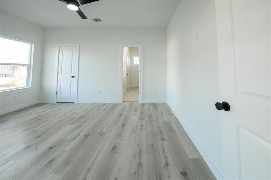 Unfurnished bedroom featuring light hardwood / wood-style floors, connected bathroom, and ceiling fan