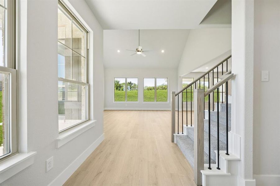 Hallway featuring lofted ceiling, light wood-style flooring, recessed lighting, and stairs