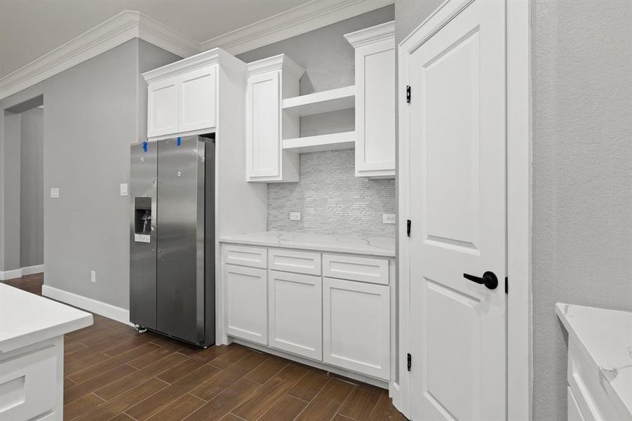 Kitchen with stainless steel fridge, ornamental molding, dark hardwood / wood-style flooring, and white cabinets