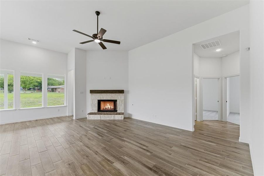 The living area features a warm fireplace with a stone surround, wood-style tile flooring, and a ceiling fan