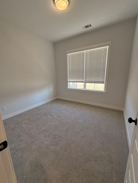 Neutral-toned carpeting, white walls, and a window with blinds