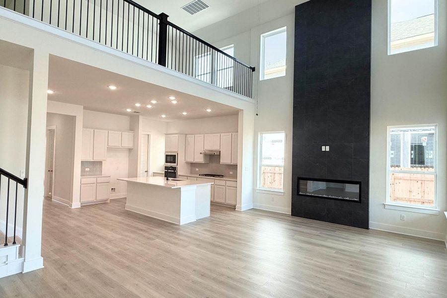 An open concept design seamlessly connects the culinary space with a two-story living area and a modern fireplace. An open concept design seamlessly connects the culinary space with a two-story living area and a modern fireplace.