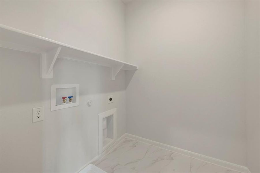 Dedicated laundry area featuring a white wall shelf, electrical outlet, washer hookups, and marble-finish flooring Dedicated laundry area featuring a white wall shelf, electrical outlet, washer hookups, and marble-finish flooring