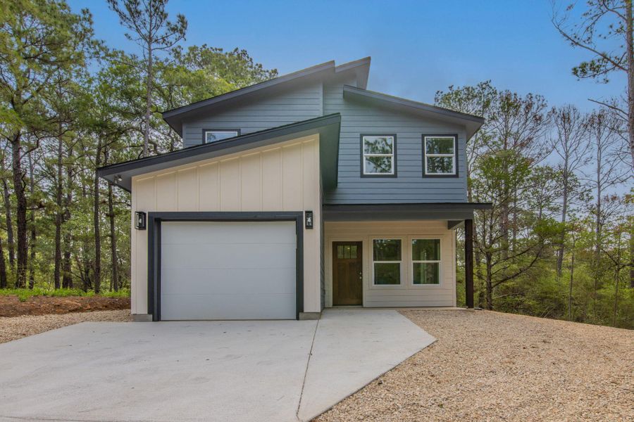 Contemporary exterior featuring a two-tone facade, attached garage, concrete driveway, and a covered entry Contemporary exterior featuring a two-tone facade, attached garage, concrete driveway, and a covered entry