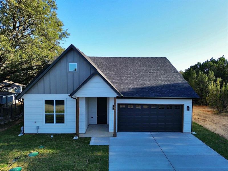 View of front of property featuring a garage and a front lawn