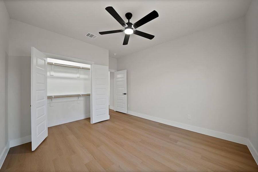 Unfurnished bedroom with light wood-style floors, a ceiling fan, and a closet Unfurnished bedroom with light wood-style floors, a ceiling fan, and a closet