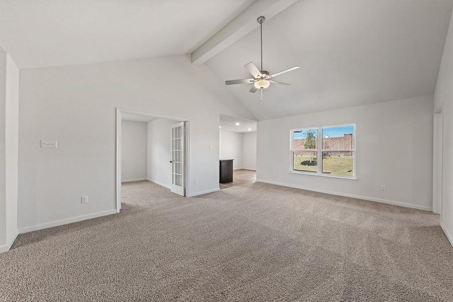 Unfurnished living room with baseboards, ceiling fan, beamed ceiling, carpet floors, and high vaulted ceiling