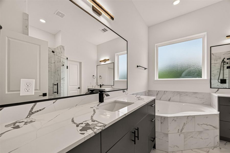 This modern bathroom features a sleek design with a large mirror, dual sinks, and elegant black fixtures. It includes a spacious walk-in shower with glass doors and a luxurious corner bathtub set against a window for natural light. Marble-like tiles add a touch of sophistication. This modern bathroom features a sleek design with a large mirror, dual sinks, and elegant black fixtures. It includes a spacious walk-in shower with glass doors and a luxurious corner bathtub set against a window for natural light. Marble-like tiles add a touch of sophistication.
