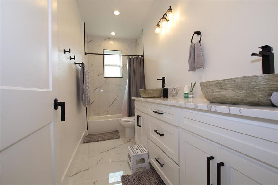 Bathroom with vanity, light marble finish floors, a combined bath / shower with marble appearance, and recessed lighting Bathroom with vanity, light marble finish floors, a combined bath / shower with marble appearance, and recessed lighting