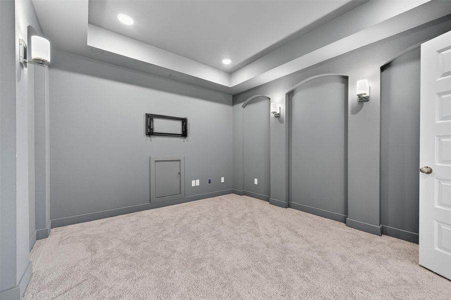Dedicated media room with tray ceilings, custom wall niches, and sconce lighting—perfect for immersive movie nights or a private entertainment retreat.