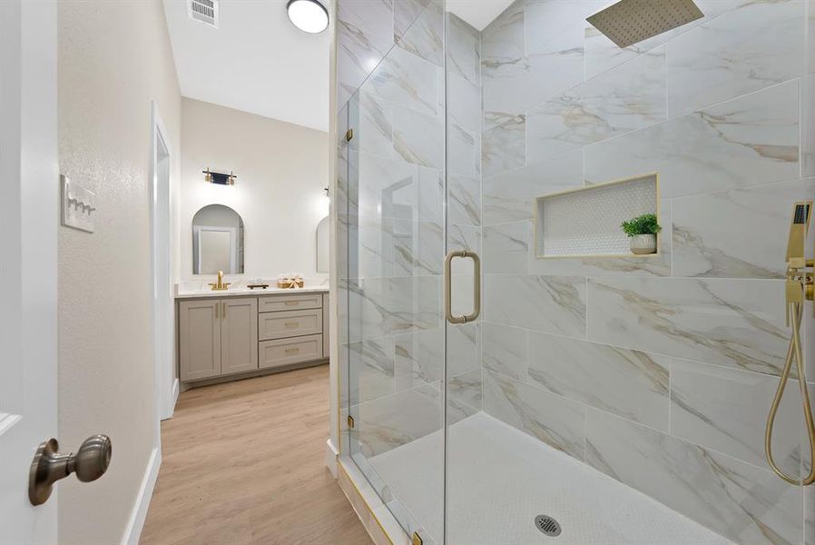 Bathroom featuring vanity, a marble finish shower, and light wood-style flooring