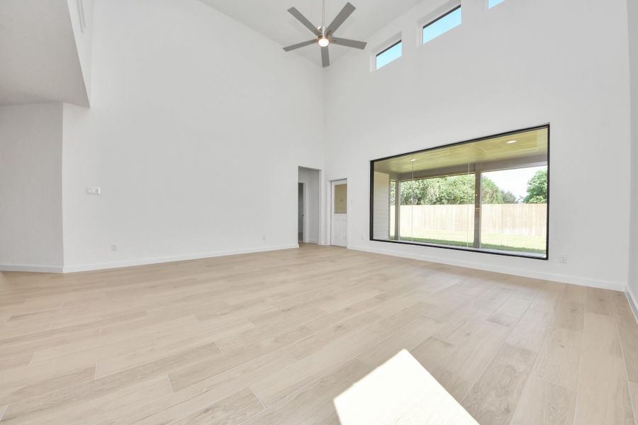 Welcome family and guests to your charming living room! With its high ceilings, recessed lighting, ceiling fan, custom paint, beautiful flooring, and large windows that let in abundant natural light, this room is perfect for gatherings. Sample photo of completed home with similar floor plan. Actual colors and selections may vary.