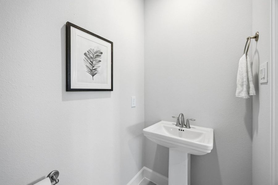 Convenient Style: The downstairs half bath combines practicality with a polished design, featuring a sleek pedestal sink and elegant fixtures, perfect for guests and everyday use.