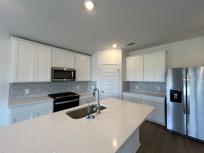 Kitchen featuring stainless steel appliances, white cabinetry, light stone countertops, decorative backsplash, and recessed lighting Kitchen featuring stainless steel appliances, white cabinetry, light stone countertops, decorative backsplash, and recessed lighting