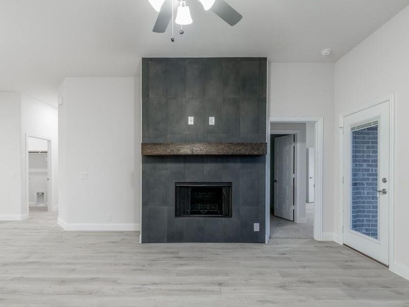 Unfurnished living room featuring ceiling fan, a fireplace, and light hardwood / wood-style floors