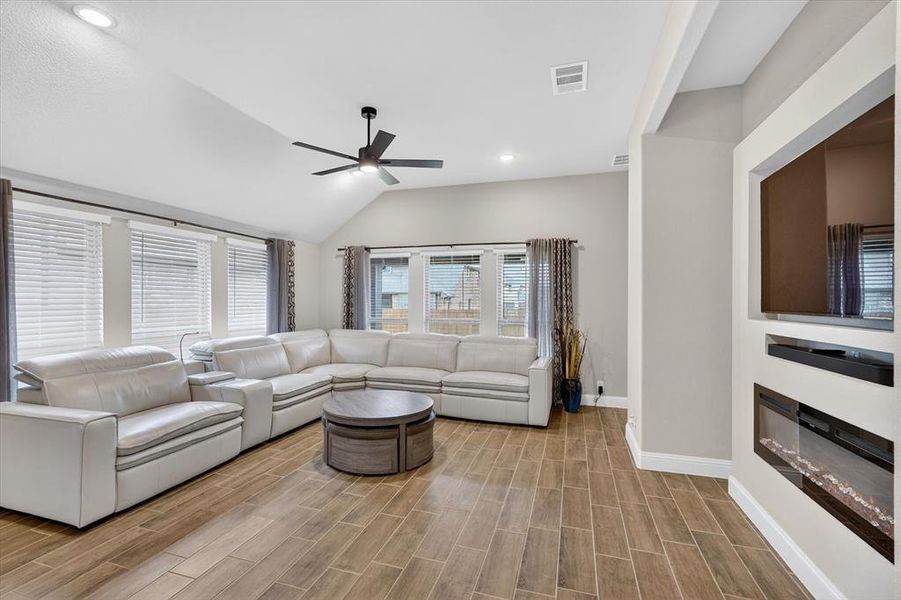 Living room featuring wood-finish flooring, vaulted ceiling, and recessed lighting Living room featuring wood-finish flooring, vaulted ceiling, and recessed lighting