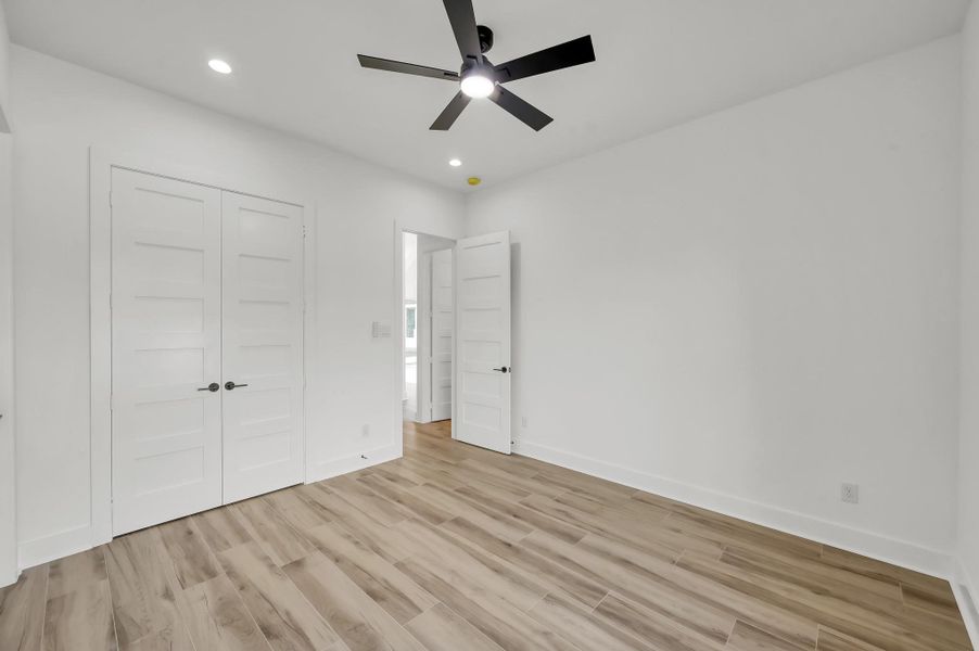 Additional bedroom offering generous floor space, double closet doors, and clean modern finishes consistent throughout the home.
