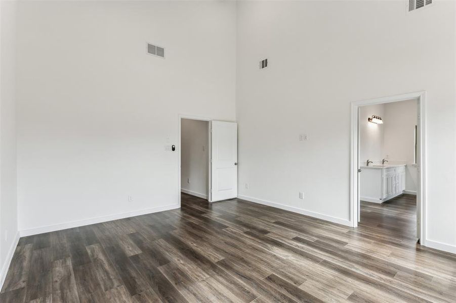 Unfurnished room featuring a towering ceiling and dark hardwood / wood-style flooring