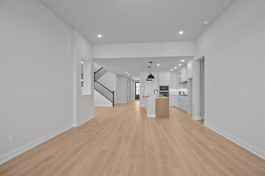 Expansive open-concept living area featuring wood-finish flooring, recessed lighting, and a neutral color palette Expansive open-concept living area featuring wood-finish flooring, recessed lighting, and a neutral color palette