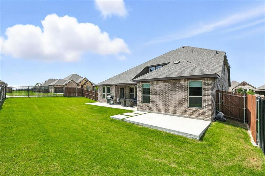 Rear view of house with roof with shingles, a patio area, brick siding, and a fenced backyard