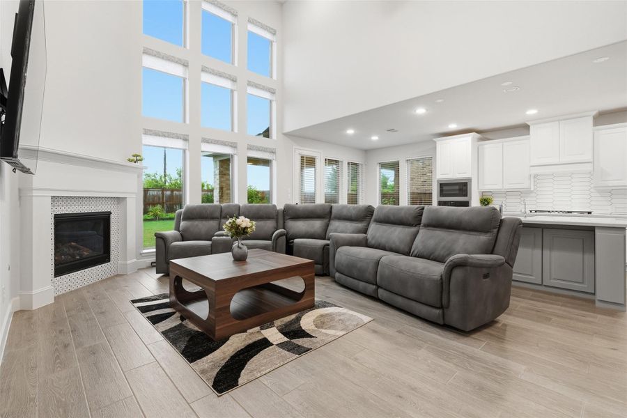 This spacious living room features high ceilings and large windows that provide plenty of natural light. It includes a modern fireplace, comfortable gray sofas, and a stylish coffee table. The open-plan design connects seamlessly to a bright kitchen with white cabinetry. This spacious living room features high ceilings and large windows that provide plenty of natural light. It includes a modern fireplace, comfortable gray sofas, and a stylish coffee table. The open-plan design connects seamlessly to a bright kitchen with white cabinetry.