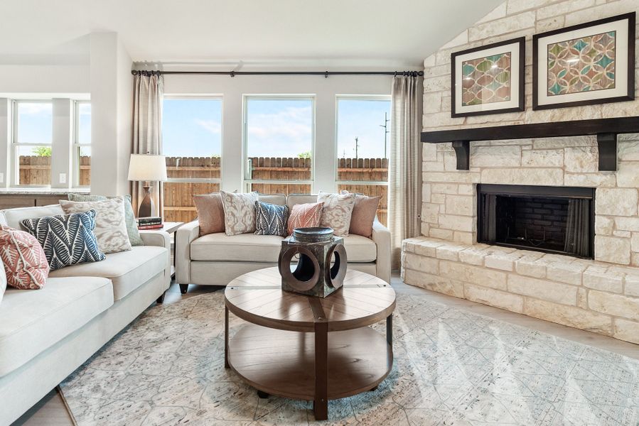 Living room with stone fireplace, two white sofas, round wood coffee table, and large windows with natural light Living room with stone fireplace, two white sofas, round wood coffee table, and large windows with natural light