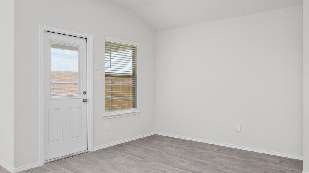 Empty room with light wood-style flooring and lofted ceiling