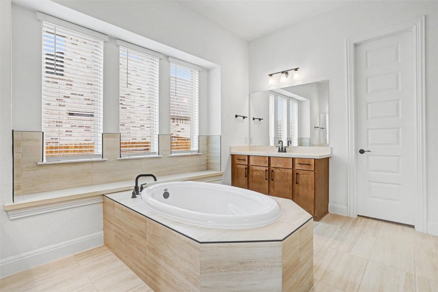 Bathroom with vanity, a garden tub, and light tile patterned floors