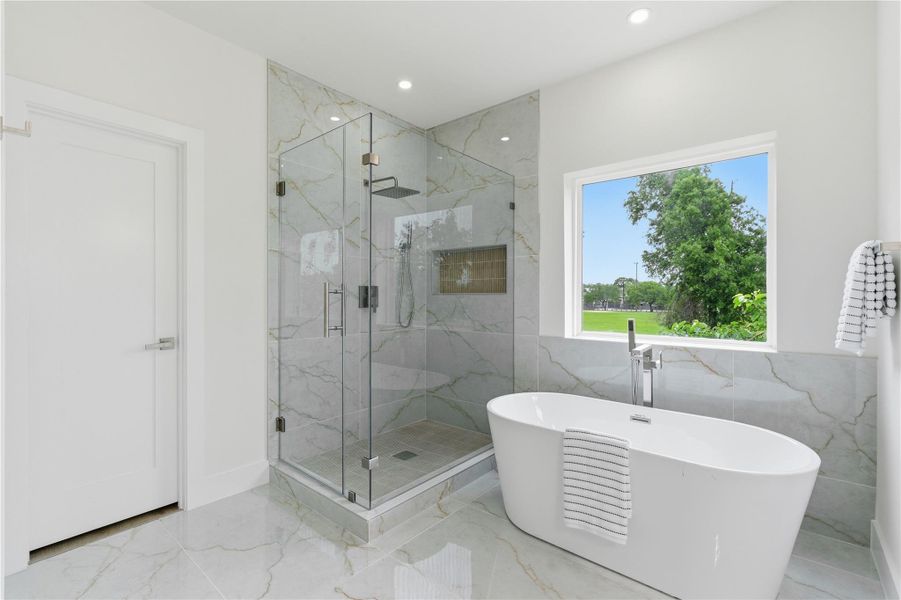 Highlighted by a glass-enclosed shower and freestanding soaking tub, the bath delivers a bright, spa-like escape.