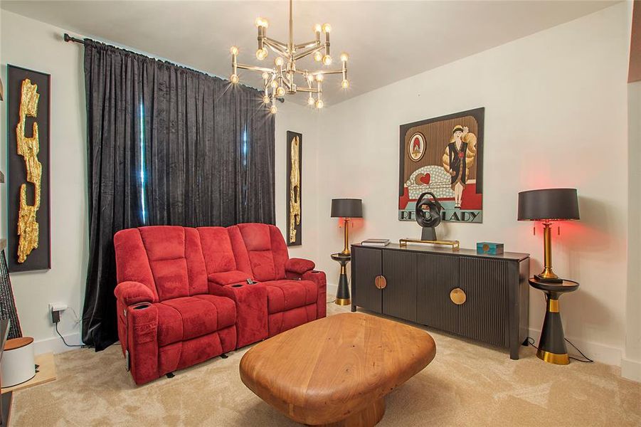 Carpeted living room featuring baseboards and a chandelier Carpeted living room featuring baseboards and a chandelier
