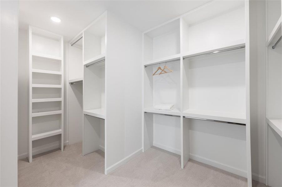 Step into a spacious, thoughtfully designed primary closet, where custom built-ins provide the ultimate in organization and style. With abundant shelving and hanging space everything has its place—making it easy to keep your wardrobe and accessories neatly arranged.