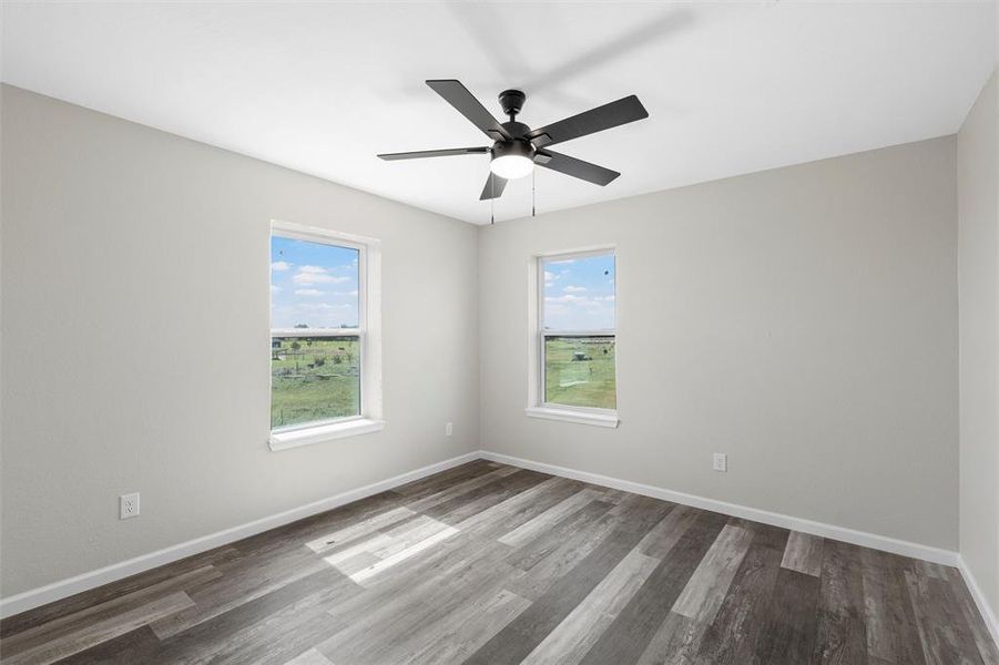 Empty room with wood finished floors and a ceiling fan Empty room with wood finished floors and a ceiling fan