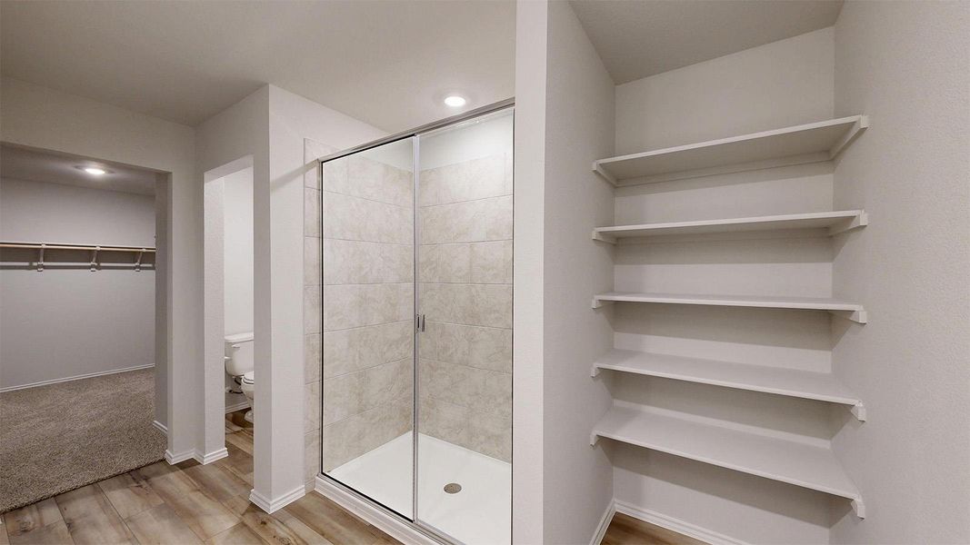 Full bathroom with a walk in closet, a shower stall, light wood-style floors, and recessed lighting