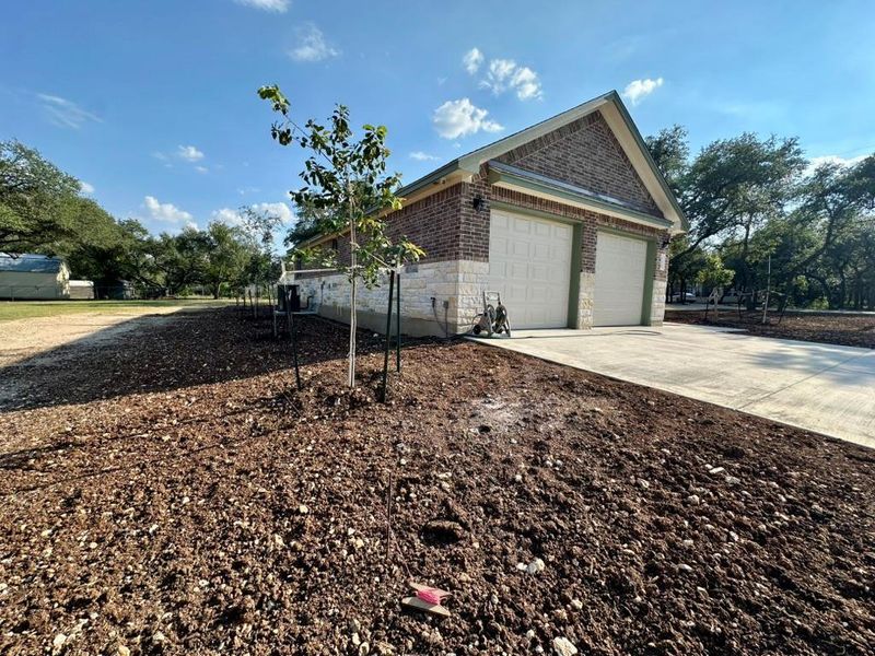 View of property exterior with driveway, stone siding, and brick siding