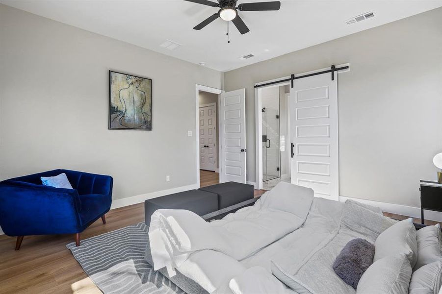 Bedroom featuring wood finished floors, visible vents, baseboards, and a barn door