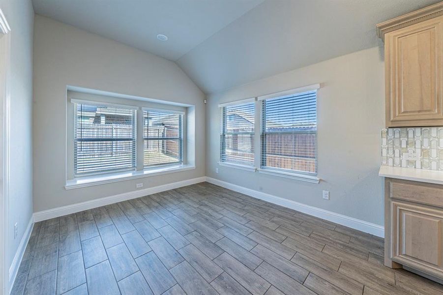 Room featuring wood-finish tile flooring, recessed lighting, and a vaulted ceiling