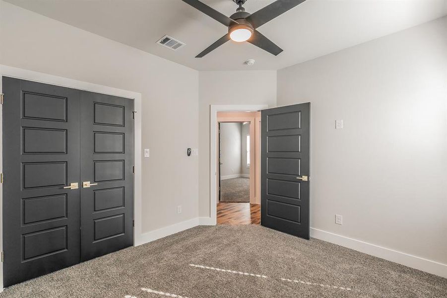 Unfurnished bedroom featuring carpet, ceiling fan, and a closet