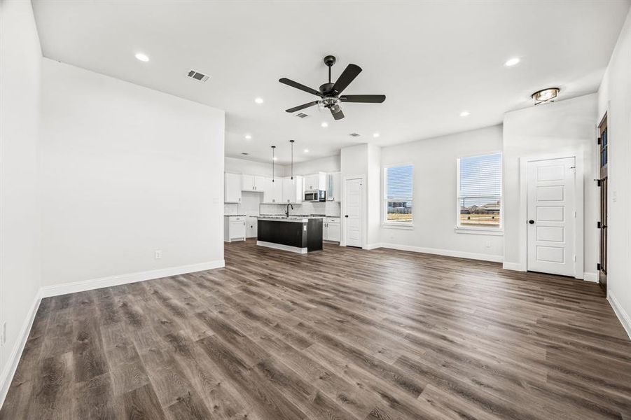 Unfurnished living room featuring dark wood-type flooring, ceiling fan, and sink