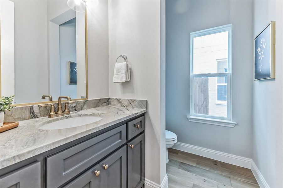 Bathroom featuring a healthy amount of sunlight, vanity, hardwood / wood-style floors, and toilet