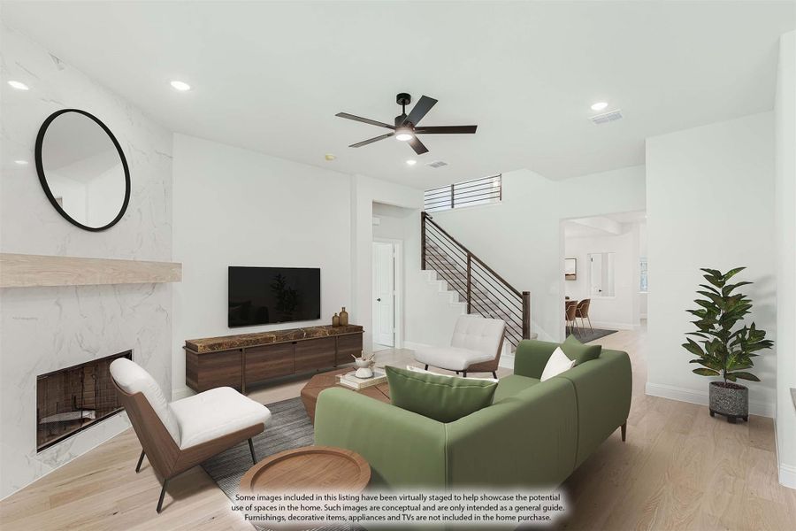Living room with marble fireplace, ceiling fan, green sofa, and staircase with modern railing