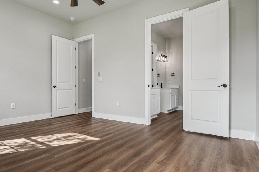 Unfurnished bedroom featuring dark wood finished floors, ensuite bathroom, recessed lighting, and a ceiling fan
