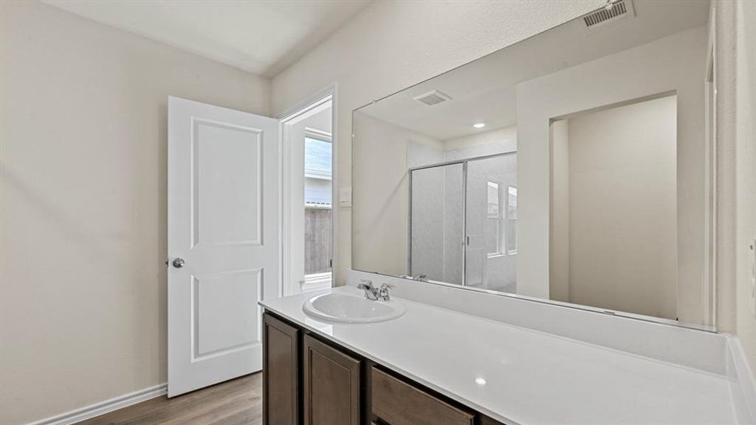 Bathroom vanity with a single sink, white countertop, and dark wood-finish cabinetry