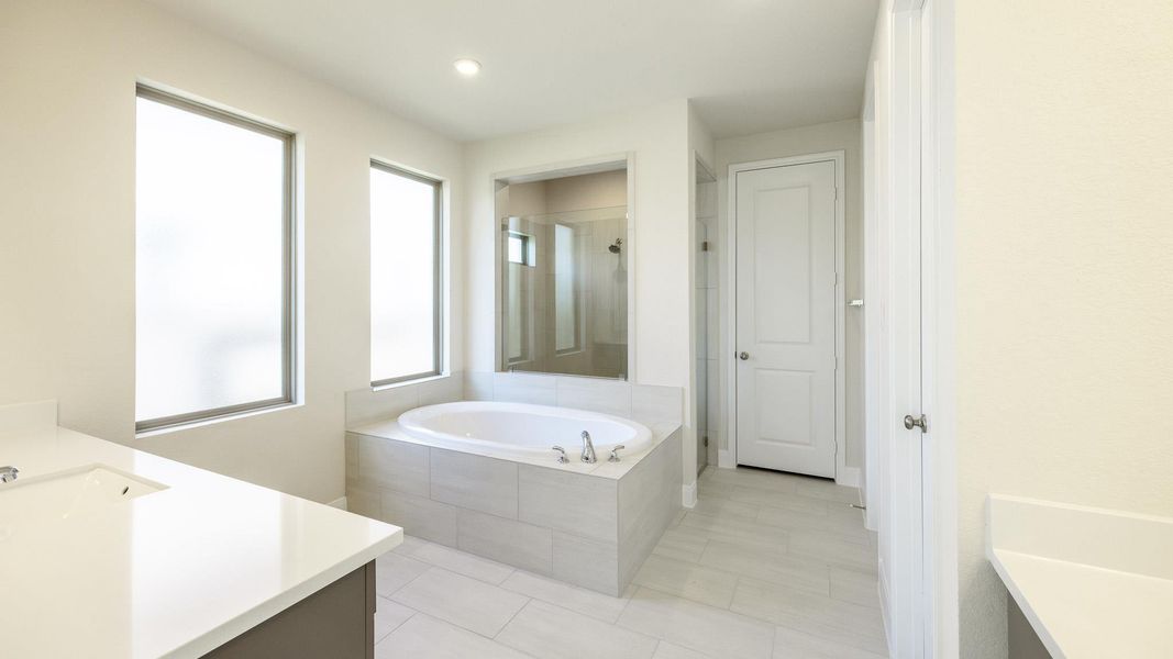 Full bathroom with a stall shower, a garden tub, vanity, light tile patterned floors, and recessed lighting Full bathroom with a stall shower, a garden tub, vanity, light tile patterned floors, and recessed lighting