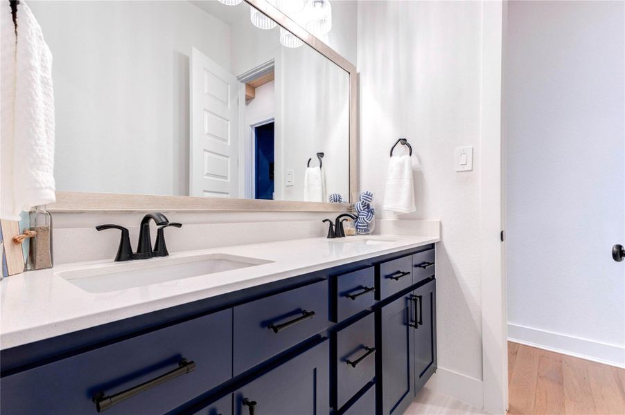 This modern bathroom features a double sink with sleek black fixtures, navy blue cabinetry, and a large mirror. It includes a separate toilet area and a shower with dark blue tiles, offering a clean and stylish look. This modern bathroom features a double sink with sleek black fixtures, navy blue cabinetry, and a large mirror. It includes a separate toilet area and a shower with dark blue tiles, offering a clean and stylish look.