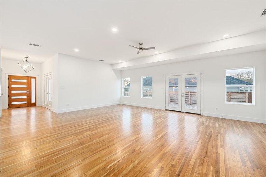 Unfurnished living room with recessed lighting, light wood-type flooring, plenty of natural light, and french doors