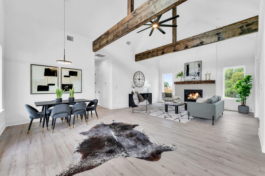 Vaulted ceilings and exposed wooden beams define this luminous open-concept living space, featuring a cozy fireplace. Vaulted ceilings and exposed wooden beams define this luminous open-concept living space, featuring a cozy fireplace.