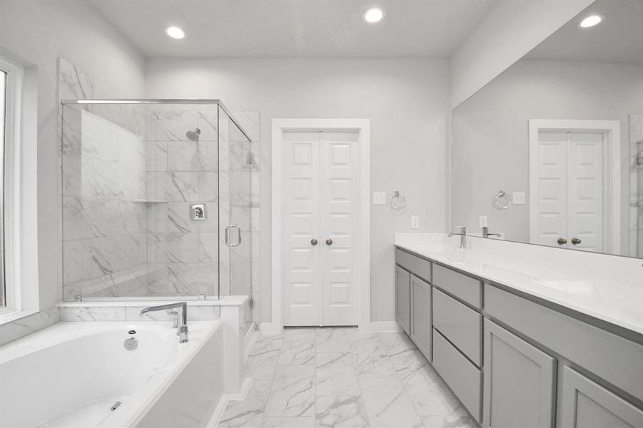 The expansive walk-in shower, surrounded by tile, and the distinctive garden tub with unique accents elevate your daily routine. The sophisticated vanity, featuring double sinks, light-colored countertops, contemporary hardware, and bright recessed lighting, adds both style and functionality to the space. Sample photo of completed home with similar floor plan. Actual colors and selections may vary.