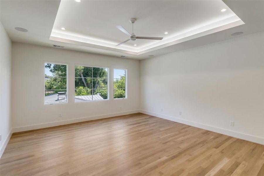Empty room featuring a raised ceiling, light wood-type flooring, recessed lighting, and ceiling fan Empty room featuring a raised ceiling, light wood-type flooring, recessed lighting, and ceiling fan